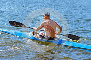 Man paddling a blue and yellow kayak on the river near the shore. Kayaking concept.A man swims in a canoe on the river. A man in a