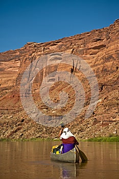 Man paddling canoe in desert canyon river