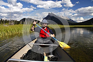 Man paddling a canoe in mountain lake