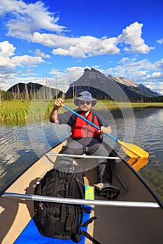 Man paddling a canoe in mountain lake