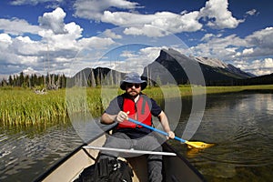 Man paddling a canoe in mountain lake