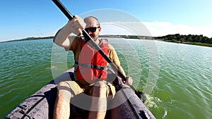 Man paddling in inflatable kayak on Vransko lake in Croatia.