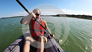 Man paddling in inflatable kayak on Vransko lake in Croatia. Adventurous kayaking experience in a beautiful nature park.