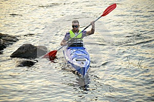 Man Paddling Kayak on Beautiful River or Lake among Stones at the Evening
