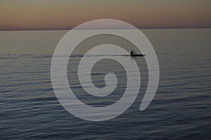 Man paddling in kayak with dramatic sunset