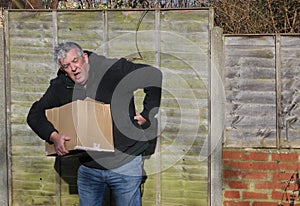 Man in pain carrying heavy box. Back strain.
