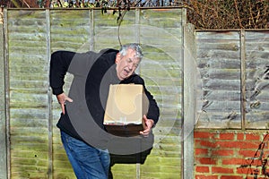 Man in pain carrying heavy box. Bad back.