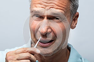 Man In Pain Removing Nose Hair With Tweezers