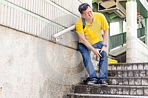Man with painful knee struggle walking down flight of stairs