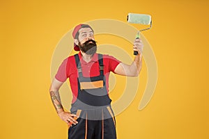 Man paint the wall. hipster builder in cap yellow background. erector assistant in work uniform. engineer designer ready