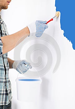 Man with paintbrush and pot painting wall