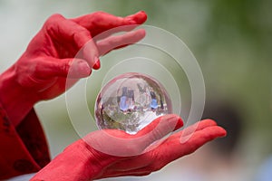 Man with painted red hands picks invisible hair off crystal ball