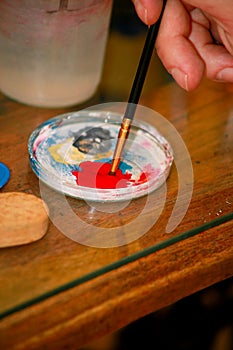 Man painter is mixing colors before painting at art paint studio. Artist in his hand holding paintbrush mixed color oil paints.