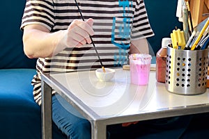 Man painter is mixing colors before painting at art paint studio. Artist in his hand holding paintbrush mixed color oil paints.