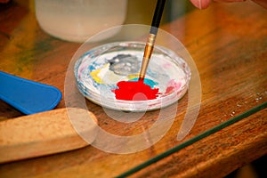 Man painter is mixing colors before painting at art paint studio. Artist in his hand holding paintbrush mixed color oil paints.