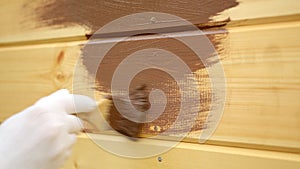 Man painter in protective suit is painting house wall using brush, hand closeup.