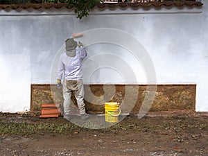 A man painting an exterior white wall of a house