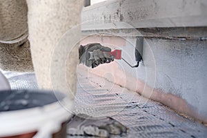 Man painting home socle with paint roller. Close up of rolling grey paint on building plinth. Home renovation