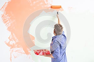 Man painting interior wall of new house. Redecoration, renovation, apartment repair and refreshment concept. Back view