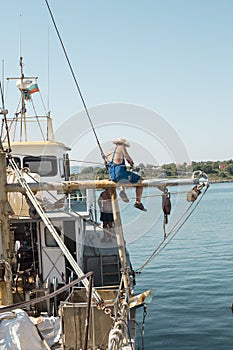 A man painting mast on his small boat