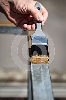 Man is painting a metal railing with copper varnish