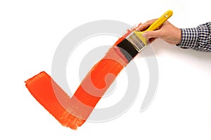 Man painting red checkmark or tick, holding paintbrush, white background