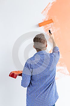 Man with painting roller indoors. Redecoration, renovation, apartment repair and refreshment concept. Back view.