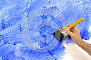 Man painting wall, holding paintbrush, blue paint, copy space