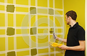 Man painting wall with masking tape