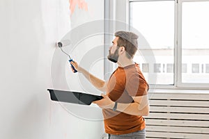 Man painting wall with paint roller - renovation and redecoration concept