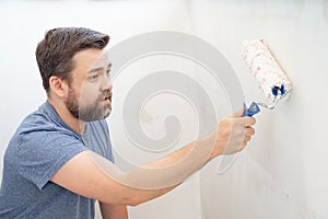 Man painting wall roller with white paint
