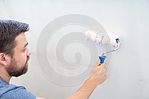 Man painting wall roller with white paint