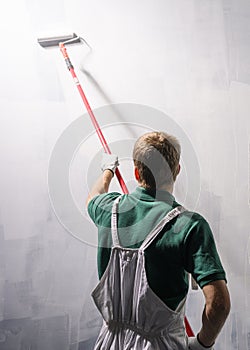 Man painting a wall in white color