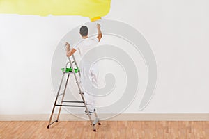 Man Painting Wall With Yellow Paint Roller
