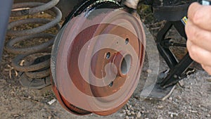 Man paints in black color rust brake caliper before replacing the wheel.