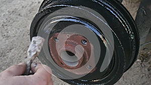 Man paints in black color rust brake caliper before replacing the wheel.
