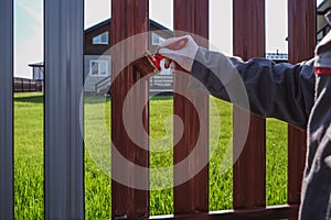 A man paints an iron fence in the garden