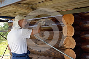 Man paints a log house