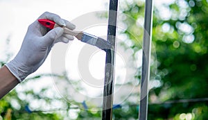 a man paints metal with black paint with a brush