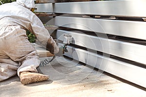 A man paints a metal tube with a pulverizer