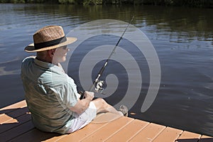 Man in a Panama Hat Sitting on Dock Fishing