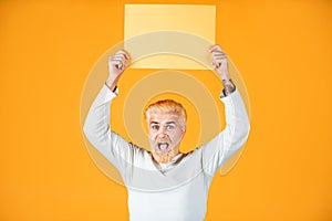 Man with paper blank advertising board on color background. Male model holding white board. Copy space for advertising.