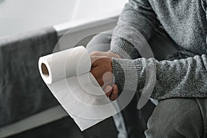 man with a paper roll in his hand sitting in the toilet