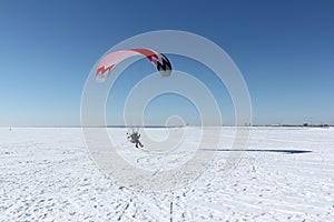 Man with a parachute and a motor, flying in the sky on a winter