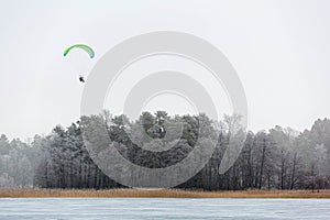 Man with parachute paragliding high in the air above hoarfrost t