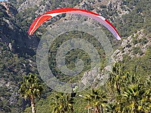 A man on a parachute wing lands in the mountains
