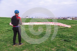 Man with paraplane in green field after landing