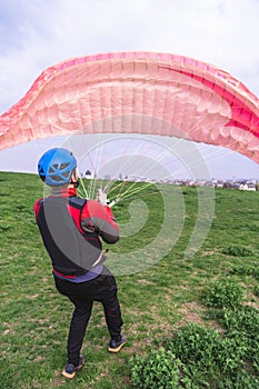 Man with paraplane starting to fly from hill top