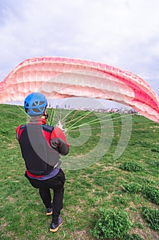 Man with paraplane starting to fly from hill top