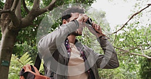 Man in park, camera and photographer in nature, tourist and travel, happy and creativity. Male person smile, artist and